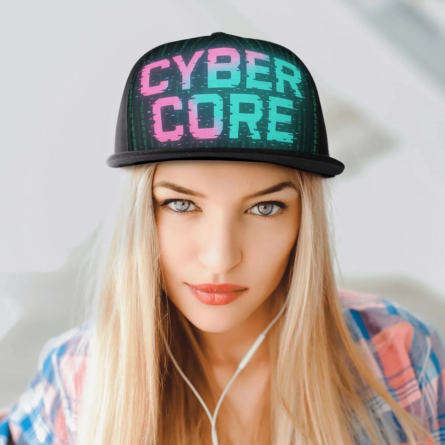 Young woman with blonde hair wearing a "Cyber Core" hat and a plaid shirt, looking at the camera.